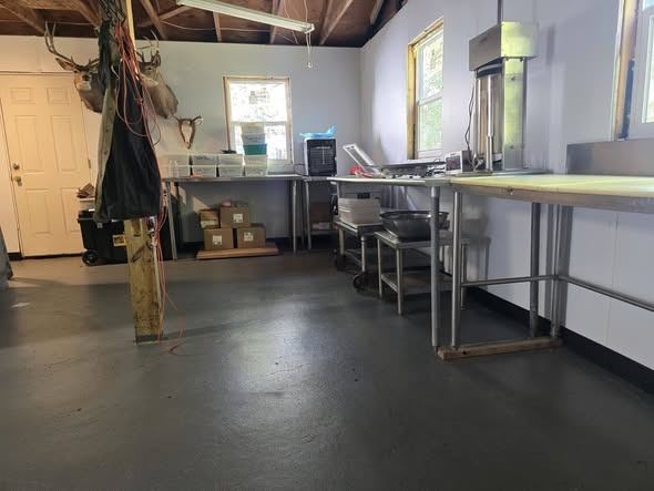 Inside the processing room: stainless-steel work tables, a sausage stuffer and deer mounts on the wall