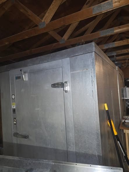 Stainless-steel walk-in cooler under wooden rafters